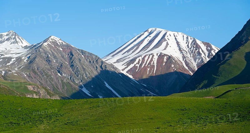 Majestic snow-capped mountains with green fields in the foreground, landscape between Kvesheti and Gudauri, Mtskheta-Mtianeti region, Georgian Military Route, High Caucasus, Georgia