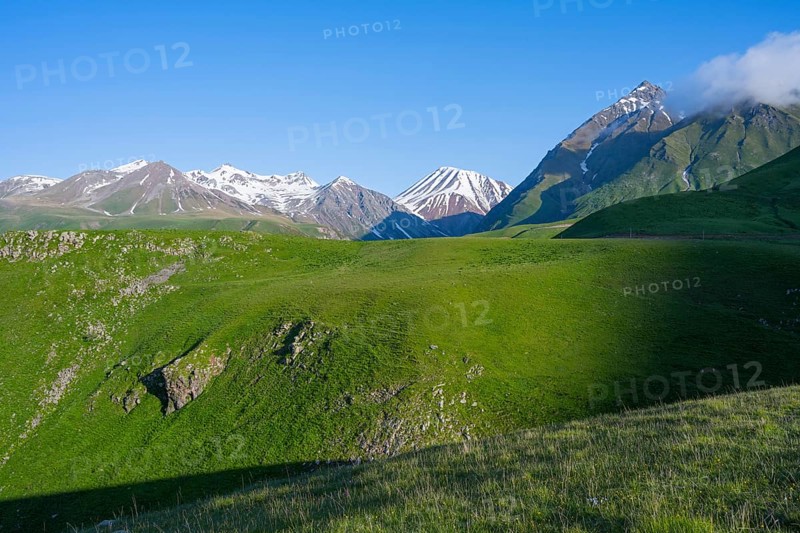 Green landscape with a vast expanse of mountains and snow-capped peaks, landscape between Kvesheti and Gudauri, Mtskheta-Mtianeti region, Georgian Military Highway, High Caucasus, Georgia