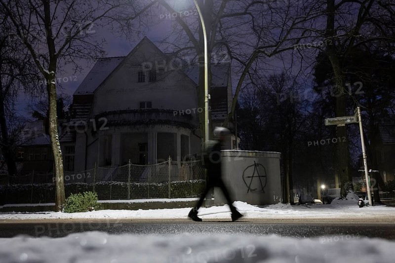 A person walks past a dark villa with an anarchy symbol written on the wall during the large-scale power outage in the Steglitz-Zehlendorf district, Berlin, 06.01.2026