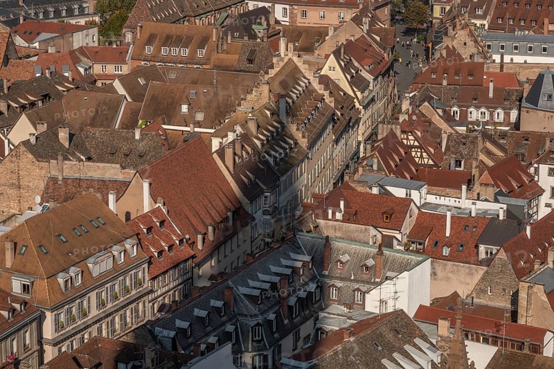 The stone balcony offers a view of the city of Strasbourg. Houses and buildings can be seen under a cloudy sky. Architectural details surround the balcony. Bas Rhin, Alsace, France
