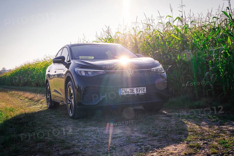 Black car on a dirt road next to a corn field with bright sunlight on the hood, VW ID5 electric car, deer e-car sharing, Calw, Germany