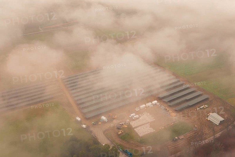 Construction site with solar systems in a foggy landscape, several vehicles visible, Energiewende, construction of PV open space, Baden-Württemberg, Germany