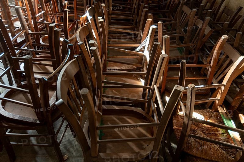 Many old wooden chairs are stacked in disarray, upside down in a church. France. Europe