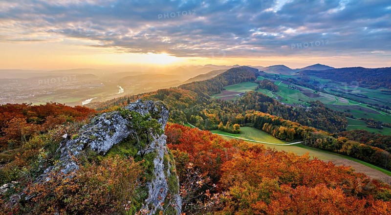 View from the Gisliflue of an autumn-colored forest, behind the Jurassic foothills with water fluh and stripes in the light of the setting sun, Talheim, Canton, Aargau, Switzerland
