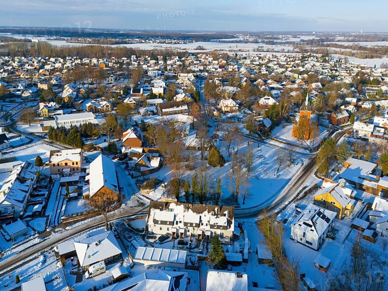 Snowy town view with many houses, a church and snow-covered roads, aerial view, Trinity church, Oelsburg, municipality of Ilsede, district of Peine, Lower Saxony, Germany