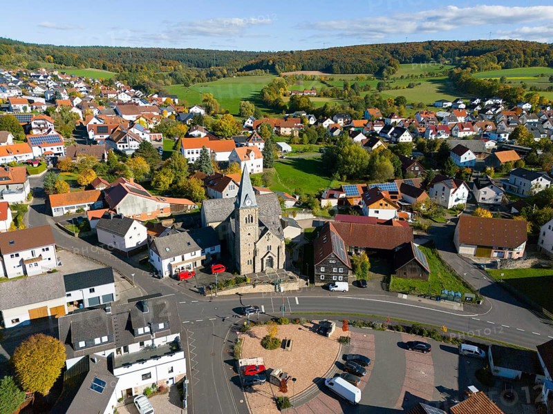Aerial view of a village church on a square surrounded by autumn trees, aerial view, Niederkalbach, Kalbach municipality, Fulda district, Hessian Rhön nature park Park, Hesse, Germany