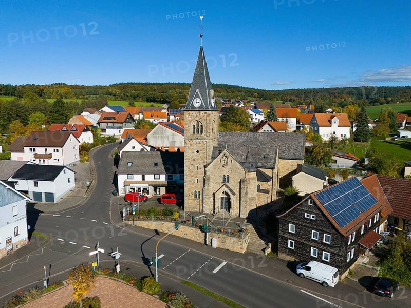 Close-up of a church in a village surrounded by roads and modern houses, aerial view, Niederkalbach, Kalbach municipality, Fulda district, Hessian Rhön nature park Park, Hesse, Germany