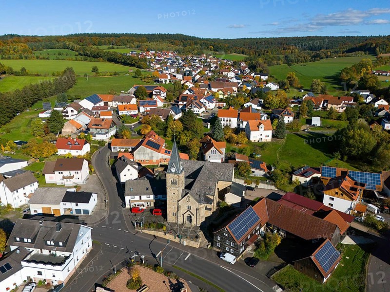 Aerial view of a village with church and many houses in an autumn landscape, Niederkalbach, Kalbach municipality, Fulda district, Hessian Rhön nature park Park, Hesse, Germany