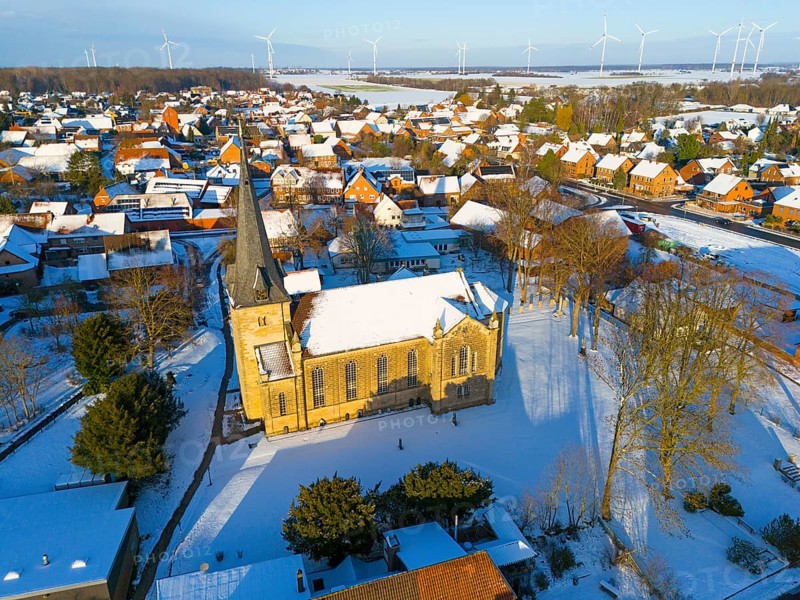 Snowy church in a village with a rural atmosphere, surrounded by wind turbines in a quiet winter landscape, aerial view, Bernwardskirche, Groß Lafferde, municipality of Ilsede, district of Peine, Lower Saxony, Germany