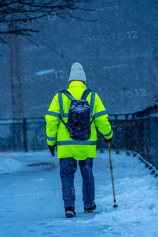 Winter weather, blowing snow, man walking on a snowy sidewalk with a walking stick, North Rhine-Westphalia, Germany