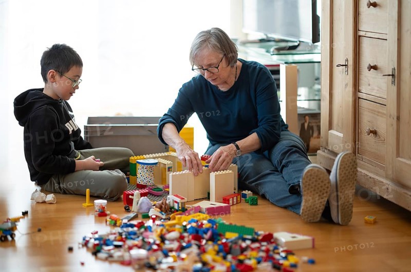 Elderly woman, grandma, boy, 6 years, grandson, glasses, multi-ethnic, playing together with Lego, concentrating, constructing, building, Stuttgart, Baden-Württemberg, Germany