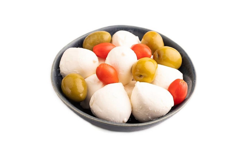 White Mozzarella cheese, with tomatoes and olives in blue bowl Isolated on white background, side view, close up