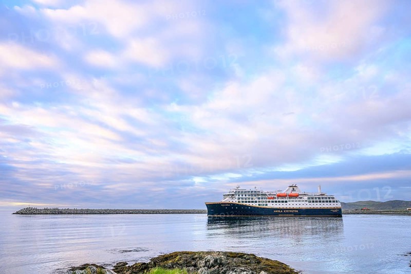 Cruise ship Havila Capella of Havila Kystruten competitor to Hurtigruten in Berlevag harbour, rocks in the foreground, quiet atmosphere, Berlevåg, Finnmark, Norway