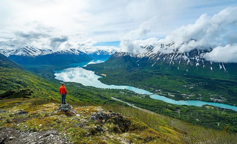 Climber enjoying the view, Slaughter Ridge Trail, view of snowy mountains and turquoise blue Kenai Lake, Cooper Landing, Kenai Peninsula, Alaska, USA
