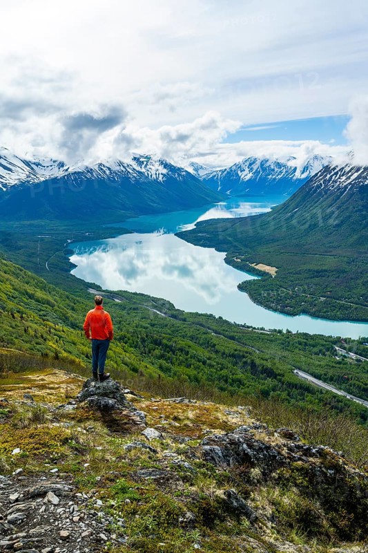 Climber enjoying the view, Slaughter Ridge Trail, view of snowy mountains and turquoise blue Kenai Lake, Cooper Landing, Kenai Peninsula, Alaska, USA