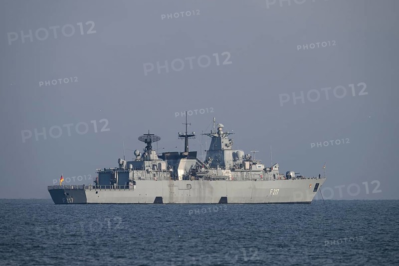 A gray naval vessel from the submarine defense the frigate Bayern F217 on calm seas at roadside off the island of Heligoland in clear skies, Heligoland, Schleswig-Holstein, Germany