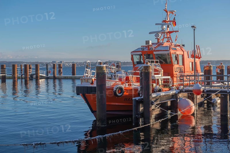 Kiel-Holtenau pilot station in front of the Kiel Canal, pilot boat, channel guidance, shipping, safety, dolphins, pier, Kiel Fjord, Baltic Sea, on the horizon east shore with Heikendorf, calm sea, winter, snowfall, sunshine, blue sky, Kiel, Germany