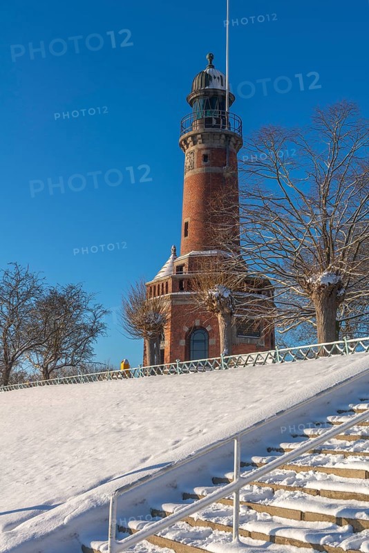 Holtenau lighthouse at the entrance of the Kiel Canal in winter, west bank of the Kiel Fjord, shipping, brick building from 1895, round tower, orientation, sea sign, beacon, ground floor with wedding room, trees, hills, steps, snow, blue sky, Baltic Sea, Kiel, Germany