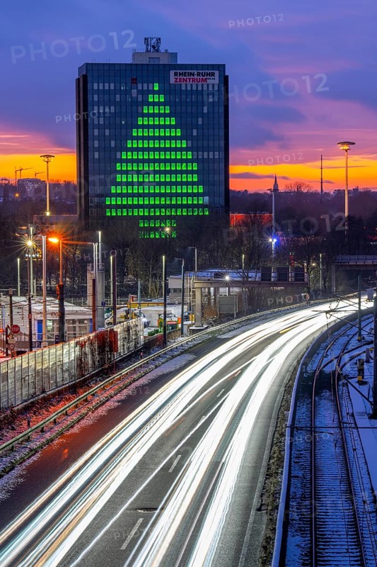 Autobahn A40, Ruhrschnellweg, between Essen and Mülheim an der Ruhr, evening traffic in winter, former, now vacant Stinnes high-rise building, at the Rhine-Ruhr Center, showing a green Christmas tree from illuminated windows at Christmas time, North Rhine-Westphalia, Germany