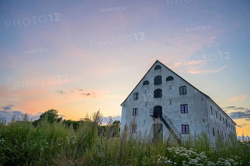A historic stone building under a colorful evening sky at sunset, old merchant magazine, Südpunkt Sweden, Skane län, Sweden