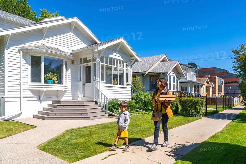 Mother and son are walking back home after picking up a food delivery order on a sunny summer day in a residential neighborhood of calgary, alberta, canada