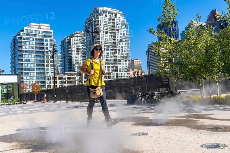 Female tourist walking in a foggy square in calgary city center during a sunny summer day, enjoying her urban exploration of the canadian metropolis