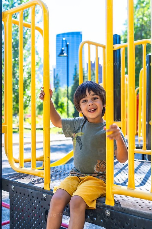 Happy child smiling and playing joyfully on a vibrant playground structure in calgary, canada, relishing the warmth of a sunny summer day outdoors in the park