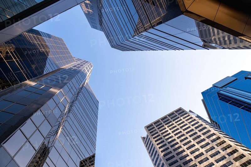 Low angle view of modern skyscrapers in calgary, canada, emphasizing their height and contemporary design against a clear blue sky, symbolizing urban growth