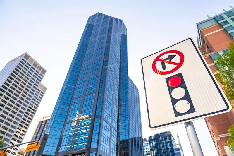 Low angle view of a no right turn sign and traffic light against towering modern skyscrapers in calgary, alberta, highlighting urban development and traffic regulations
