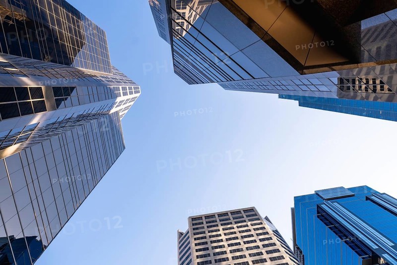 Low angle view of modern skyscrapers in calgary, alberta, canada, showcasing their impressive height against a clear blue sky, creating a powerful symbol of urban growth and architectural prowess