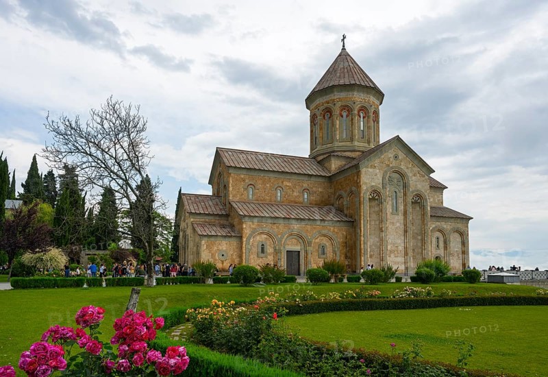 A historic church surrounded by a well-kept garden and blooming flowers under cloudy sky, Bodbe monastery, Sighnaghi, Signagi, Kakheti province, Greater Caucasus, Georgia, Western Asia