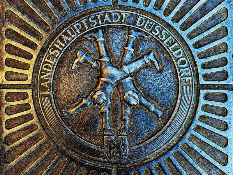 Manhole cover with classic depiction of the racket, landmark of the state capital Düsseldorf, North Rhine-Westphalia, Germany