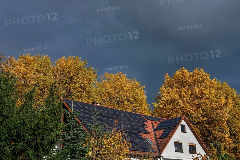 Stormy atmosphere with autumn trees and house with photovoltaic on the roof, Eckental, Middle Franconia, Bavaria, Germany
