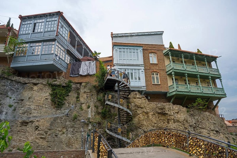 Traditional buildings with wooden balconies stand on a rock with a spiral staircase, Abanotubani Spa District, Old Town, Tbilisi, Tbilisi, Georgia
