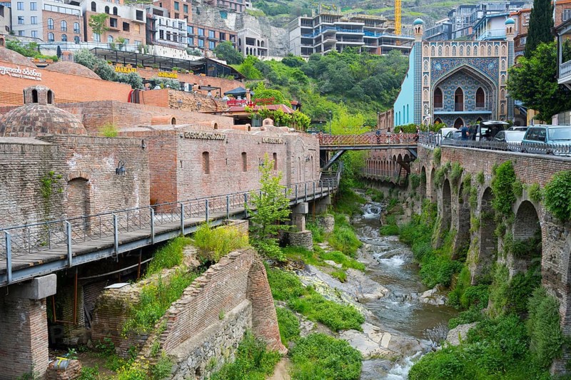 Historic bridge over a river surrounded by lush vegetation, Leghvtakhevi river and gorge, Orbeliani Bath on the right, King Erekles Bath, sulfur baths, Abanotubani spa district, old town, Tbilisi, Tbilisi, Georgia