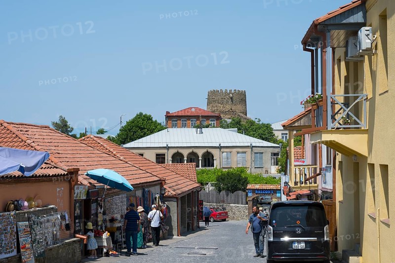 Urban street scene with people, red roofs and castle in the background, old town, Sighnaghi, Signagi, Kakheti province, Greater Caucasus, Georgia, Western Asia