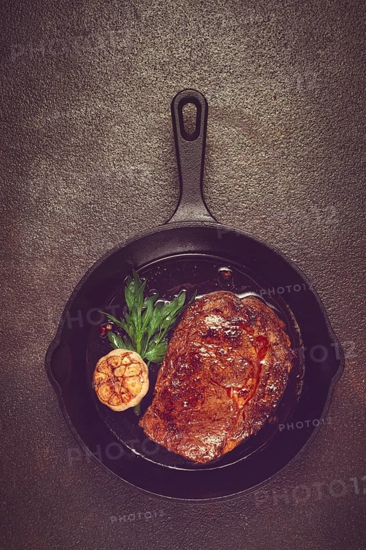 Grilled rib eye steak, in a cast-iron skillet, top view, homemade, no people