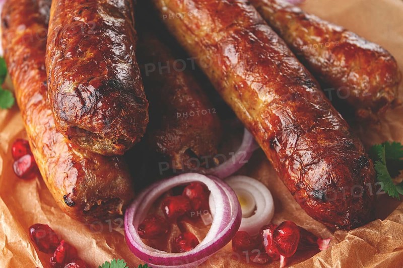 Fried kupaty on parchment, with red onion and pomegranate, kupaty, Georgian cuisine