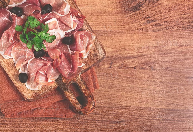 Sliced prosciutto, on a cutting board, with olives and herbs, snack, breakfast, no people