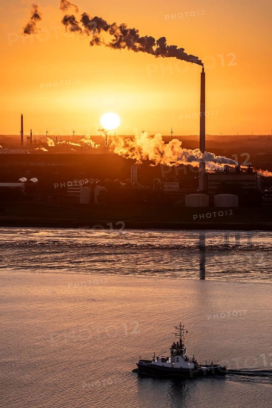 Fairplay 61 harbour tug arrives at the mouth of the Weser, in the background the Kronos Titan chemical plant, a leading global manufacturer of titanium dioxide, in Nordenham, Bremerhaven, sunset, Germany