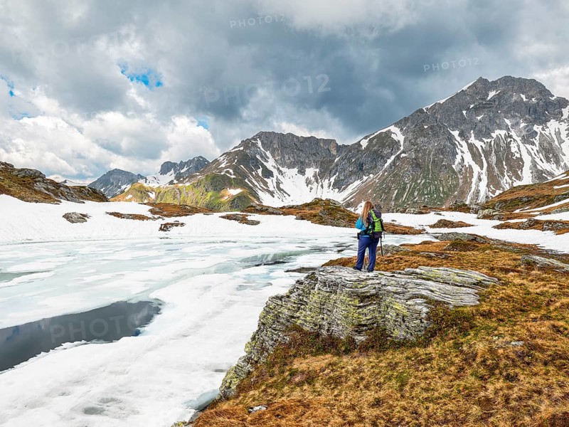 Half-frozen mountain lake with hiker, snow, Essersee, Stierkarkopf, Wildkarhöhe and Rothorn, Radstädter Tauern, Riedingtal nature park Park, Zederhaus, Lungau, Salzburg
