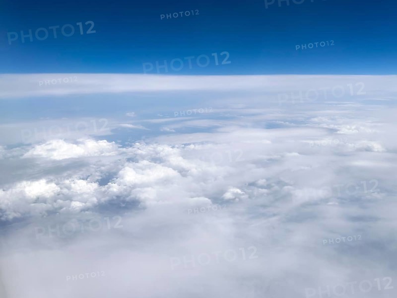View from an airplane of closed cloud cover in it white bright cluster clouds cirrus clouds on the left, international
