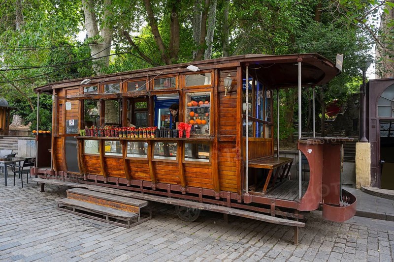 Wooden tram as a food stand with fruit in cups on a tree-lined cobblestone street, tram bar, old tram car, Tbilisi, Tbilisi, Georgia
