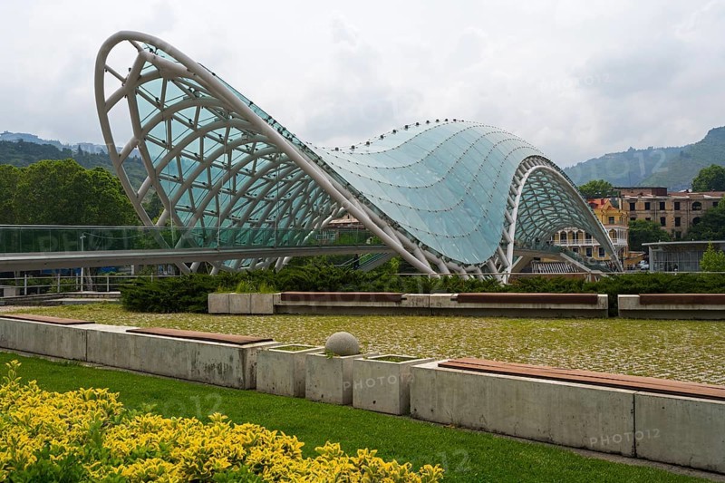 Modern glass roof of a bridge in wave form with surrounding park area, Peace Bridge, Rike Park, Tbilisi, Kura River, Georgia