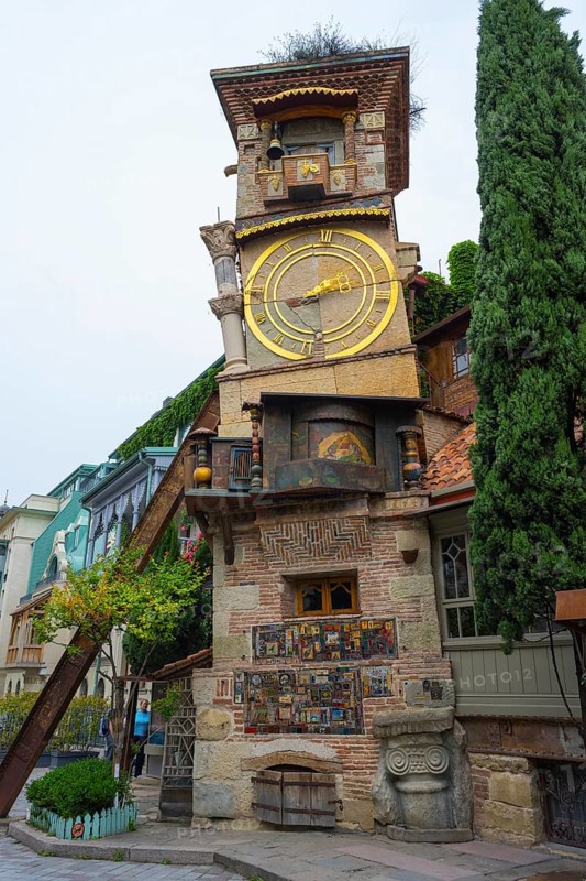 An old building with a big clock in a charming architectural style, surrounded by trees, clock tower, landmark for the State Puppet Theater, Tbilisi, Georgia