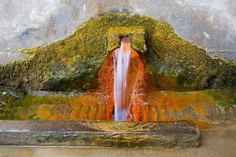 Rust-brown water flows from a spring in a concrete wall surrounded by eroded mineral deposits, mineral spring, Bolnissi, Katharinenfeld, Lower Kartli region, Kwemo Kartli, Georgia