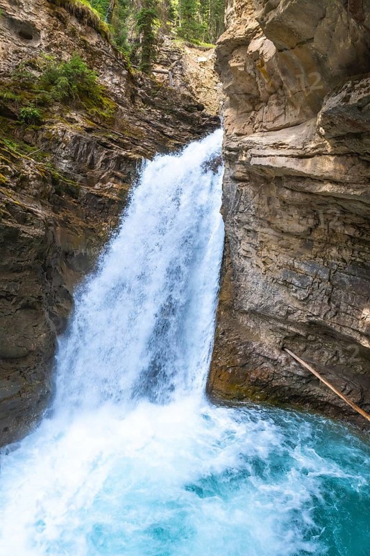 Powerful waterfall plunging into a vibrant turquoise pool in johnston canyon, creating a breathtaking spectacle of nature's beauty in banff national park, canadian rockies, alberta, canada