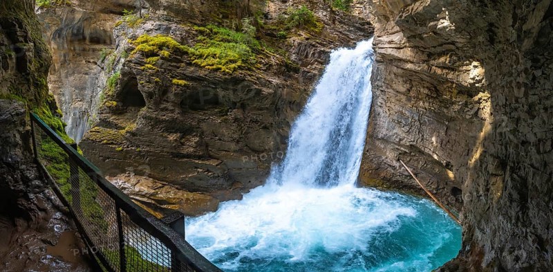 Powerful waterfall cascading into a turquoise pool in johnston canyon, surrounded by rocky cliffs and lush vegetation, creating a breathtaking natural wonder in banff national park, alberta