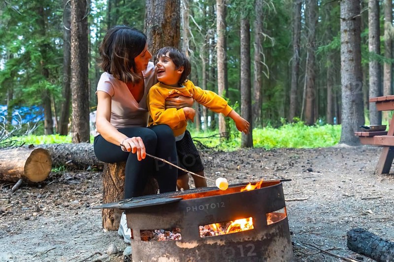 Mother and son are roasting marshmallows over a campfire in banff national park, alberta, canada, enjoying quality time together in the beautiful natural setting