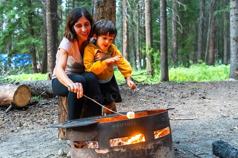 Mother and son roasting marshmallows over a campfire in banff national park, alberta, enjoying a camping trip amidst the beautiful canadian rockies